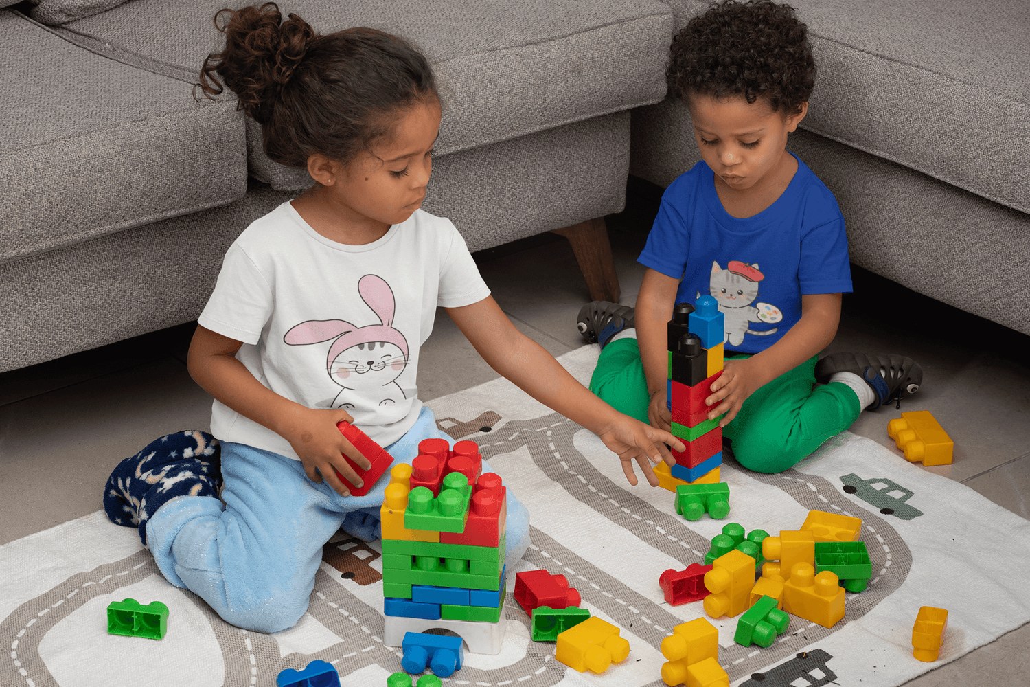 Kids playing with colorful building blocks, showcasing playful toddler tees from Joelleart Fashion Design.