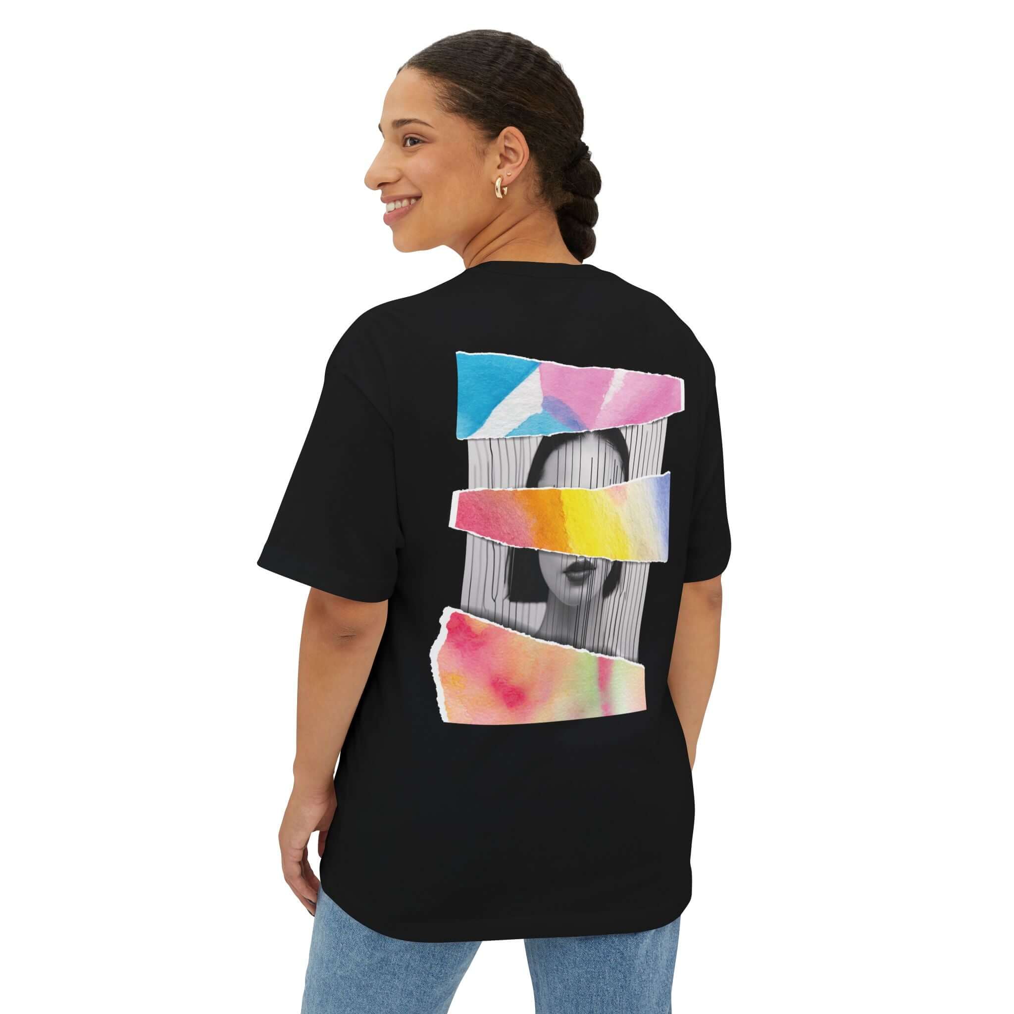 Unisex oversized black tee with colorful artistic design on the back, worn by a smiling woman, perfect for casual fashion.