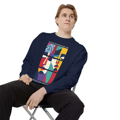 Young man wearing a colorful motivational unisex sweatshirt, seated and showcasing artistic design on a navy background.